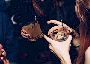 People are enjoying themselves with drinks, laughing and in conversation at what seems to be a social gathering or party.