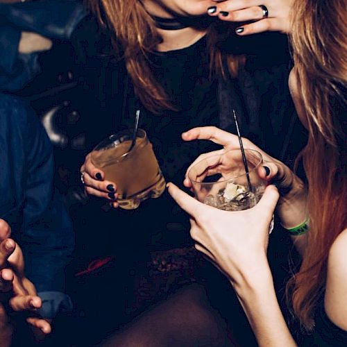 People are enjoying themselves with drinks, laughing and in conversation at what seems to be a social gathering or party.